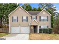 Charming two-story home featuring a two car garage, neutral siding and dark shutters at 704 Davenport Ct, Stockbridge, GA 30281