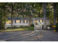 Charming single-story home with a stone chimney, wooden wheelchair ramp, and mature trees at 4226 Highway 155 N, Stockbridge, GA 30281