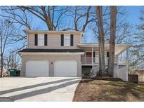 Charming two-story home with a two-car garage, brick accents, covered porch, and mature trees at 3822 Holland Dr, Snellville, GA 30039