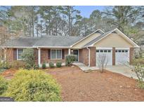 Charming brick home featuring an attached two-car garage and landscaped front yard at 618 Grecken Green, Peachtree City, GA 30269