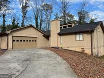 Beige single-story house featuring an attached garage and a well-maintained front yard at 1725 Sara Se Ct, Conyers, GA 30013