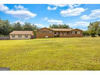 Expansive front yard showcasing a brick home with a covered porch and a detached garage at 229 Callaway Rd, Fayetteville, GA 30215