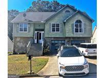 Two-story home features stone accents, wood siding, and a two-car garage at 7667 N Briar Ridge Ct, Riverdale, GA 30296