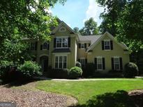 Traditional two-story home with black shutters, surrounded by mature trees and a lush green lawn at 245 Ashley Forest Dr, Fayetteville, GA 30214