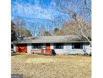 Charming ranch-style home with a red garage door, shutters, and manicured front yard at 23 Hampton Locust Grove Rd, Hampton, GA 30228