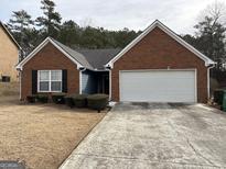 Charming single-story brick home featuring a two-car garage, complemented by green shrubbery in the front yard at 4092 Rivermist Ct, Lithonia, GA 30038