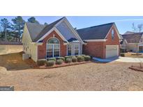 Charming home featuring a brick and siding exterior, complemented by mature landscaping and a well-manicured lawn at 227 Lantana Dr, Locust Grove, GA 30248