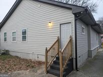 Exterior view of home featuring light colored vinyl siding, dark gutters, and a small set of wooden stairs to access a door at 1528 Olympian Sw Way, Atlanta, GA 30310