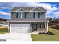 Charming two-story home features a gray exterior, well-manicured lawn, and a two-car garage with a large driveway at 452 Prescott Way, Villa Rica, GA 30180