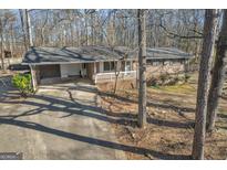 Brick home featuring attached carport, white railing, and a mature tree-lined lot at 6198 Rocky Creek Dr, Douglasville, GA 30135