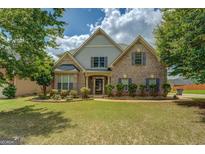 Charming two-story brick home featuring lush landscaping and a well-manicured lawn at 1186 Diamond Xing, Mcdonough, GA 30252