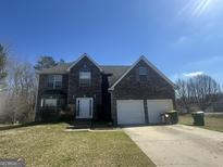 Charming two-story home featuring a stone facade, two-car garage, and manicured front lawn at 10988 Mansura Pl, Hampton, GA 30228
