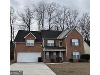 Charming two-story brick home featuring an attached garage, well-manicured lawn, and mature trees at 1571 Ravens Run, Jonesboro, GA 30236