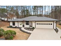 Charming single-story home with white stucco exterior, mature trees, and a well-manicured front yard at 203 Everhill, Peachtree City, GA 30269