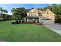 Charming brick home featuring a manicured lawn, manicured landscaping, and a welcoming front porch at 115 Woodcanoe Ct, Peachtree City, GA 30269