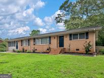 Charming single-story brick home featuring a well-manicured lawn and a classic design under a partly cloudy sky at 3 Ridge Dr, Hampton, GA 30228