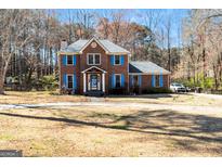 Charming brick home featuring blue shutters, a well-manicured lawn, and mature trees providing shade at 230 Mapledale Trl, Sharpsburg, GA 30277