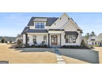 Beautiful two-story home featuring a stone and board and batten facade, covered porch, and manicured lawn at 132 Platinum Rdg, Sharpsburg, GA 30277
