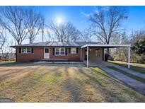 Brick home featuring a covered carport and a well-maintained front yard at 7427 Hollis Rd, Douglasville, GA 30135