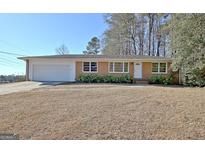 Charming brick ranch home featuring a well-manicured lawn and attached two-car garage at 940 New Hope Rd, Fayetteville, GA 30214