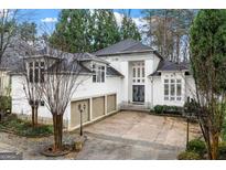 Elegant stucco home with three-car garage and double-door entry, surrounded by mature trees at 4000 Wieuca Rd Ne, Atlanta, GA 30342