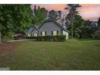 Charming home featuring a well-manicured lawn, lush greenery, and a long driveway leading to the house at 2768 Southpark Sw Blvd, Conyers, GA 30094