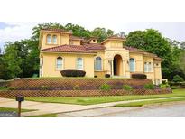 Stately two-story home with an impressive red tile roof and arched entryway, complemented by a professionally landscaped front yard at 956 Shadowford Fls, Lithonia, GA 30058