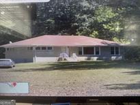 Ranch home with a gray exterior, landscaped lawn and driveway, and a partially wooded front yard at 1280 Sw Boatrock Rd, South Fulton, GA 30331