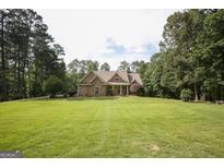 Sprawling front lawn leads up to a charming home with lush landscaping and a welcoming front porch at 8179 Pineview Ct, Villa Rica, GA 30180