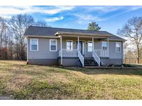 Inviting single-story home featuring a cozy front porch, well-maintained lawn and blue sky at 550 Stateline Rd, Bowdon, GA 30108