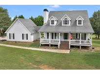 Charming home with a large front porch, gray roof, white siding, and an American flag at 2110 Mcgarity Rd, Mcdonough, GA 30252