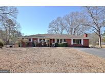 Charming brick ranch-style home with a well-maintained lawn and mature trees on a sunny day at 1019 S Jeff Davis Dr, Fayetteville, GA 30215
