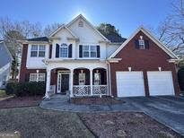 Inviting two-story home with brick accents, a covered porch, and a well-manicured front lawn at 5725 Lake Windsor Pkwy, Buford, GA 30518