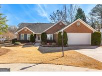 Charming single-Gathering brick home featuring a well-manicured lawn and an attached two-car garage at 165 Hunters Walk, Fayetteville, GA 30214