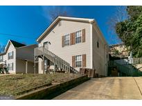 Two-story home with light siding, brown shutters, and a wooden staircase leading to the entrance at 5365 Renault St, Cumming, GA 30041