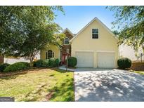 Charming yellow two-story home with a well-manicured lawn and a two-car garage in a great neighborhood at 545 Goldfinch Way, Stockbridge, GA 30281