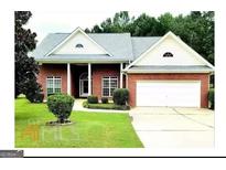 Charming one-story brick home with well-manicured lawn and two-car garage at 13271 Woolsey Rd, Hampton, GA 30228