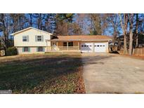 Charming home featuring a brick-and-siding facade, a spacious front yard, and an attached two car garage at 2150 Lisbon Ln, Jonesboro, GA 30236
