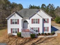 Two story home featuring classic white siding and red shutters with a lawn and mature trees at 231 Ashley Trace Dr, Locust Grove, GA 30248