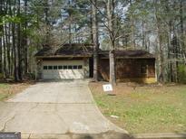 Quaint home with a stone and wood exterior, featuring an attached garage and a spacious driveway at 3208 Berrong Way, Stone Mountain, GA 30087