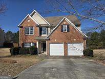 Charming two-story brick home featuring an attached two-car garage and meticulously maintained landscaping at 4561 Plantation Mill Trl, Buford, GA 30519