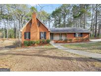 Charming brick home with a welcoming front porch and mature trees at 105 Jasper Dr, Stockbridge, GA 30281