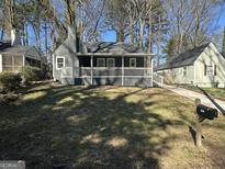Charming gray home featuring a covered front porch, a well-maintained lawn, and mature trees at 1457 Richland Sw Rd, Atlanta, GA 30310