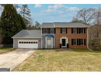 Charming two-story home featuring a brick facade, gray siding, bay window, and a two-car garage at 1399 Fawnbrook Ct, Lilburn, GA 30047