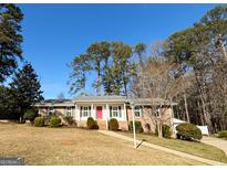 Charming single-story home with a brick facade, manicured lawn, and vibrant red front door, creating a welcoming curb appeal at 107 Cannongate Cir, Sharpsburg, GA 30277