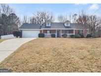 Charming one story brick home with a well manicured lawn, two dormers, and an attached two car garage at 12 Bonnie Glen Ln, Hampton, GA 30228