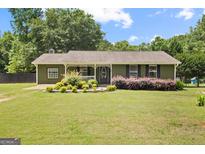 Charming single-story home with a well-manicured lawn, flowerbeds, and a cozy front porch at 888 Laney Rd, Locust Grove, GA 30248