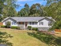 Charming single-story home with white siding, blue shutters, and a well-manicured lawn and mature trees at 5 Ridgewood Cir, Mcdonough, GA 30252