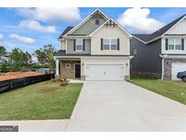 Charming two-story home featuring stone accents, a two-car garage, and a well-manicured lawn under a sunny sky at 11192 Cornerstone Way, Hampton, GA 30228