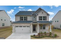 Charming two-story home featuring a brick and siding exterior, attached two-car garage, and a well-manicured front yard at 1720 Goodwin Dr # 75, Hampton, GA 30228